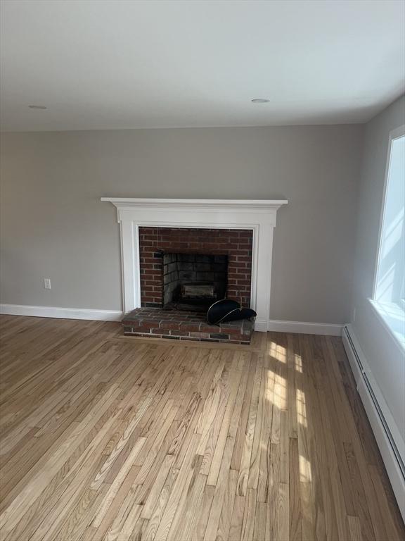 23 Town Hall Ave, Yarmouth, MA 02664 - room details featuring a baseboard heating unit, baseboards, a brick fireplace, and wood finished floors