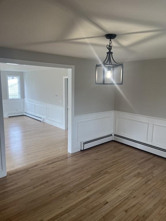 23 Town Hall Ave, Yarmouth, MA 02664 - unfurnished dining area featuring wood finished floors, a decorative wall, and wainscoting