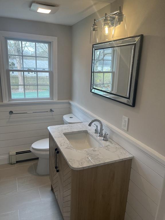 23 Town Hall Ave, Yarmouth, MA 02664 - half bathroom featuring a baseboard radiator, tile patterned floors, wainscoting, vanity, and toilet