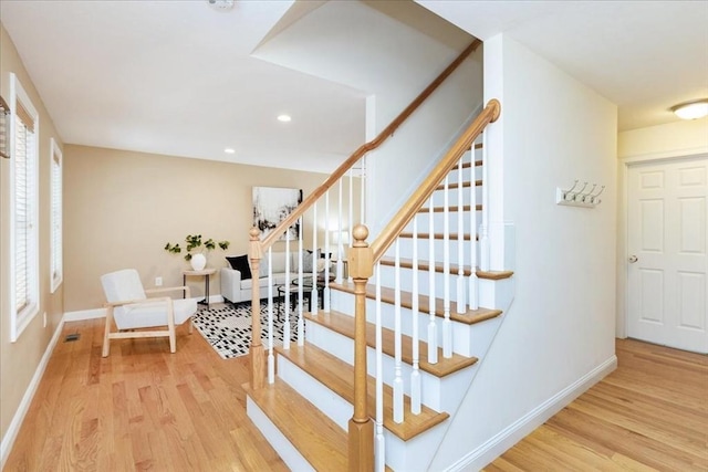 stairs with baseboards, wood finished floors, and a healthy amount of sunlight