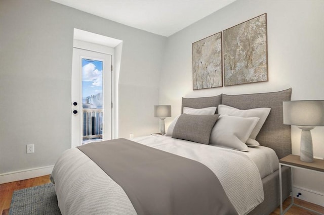 bedroom with baseboards, wood finished floors, and access to exterior