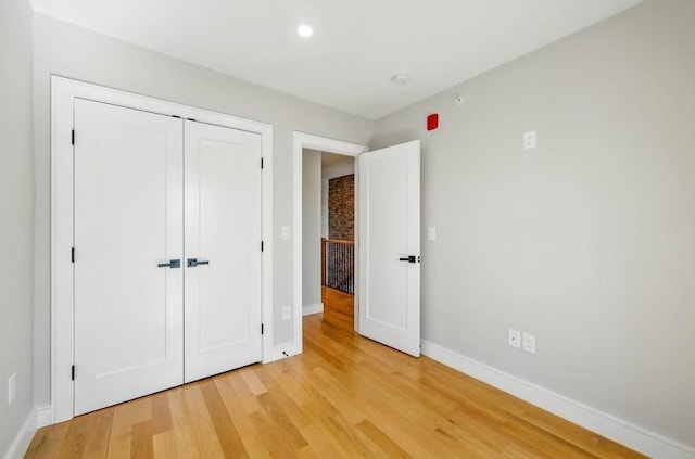 unfurnished bedroom featuring baseboards, recessed lighting, light wood-style flooring, and a closet