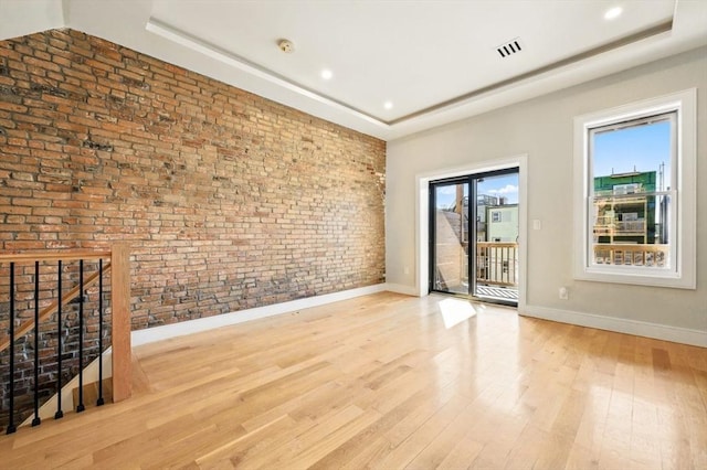 spare room featuring baseboards, visible vents, wood finished floors, and a raised ceiling