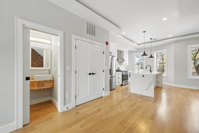 kitchen with a sink, appliances with stainless steel finishes, light wood-style flooring, and visible vents