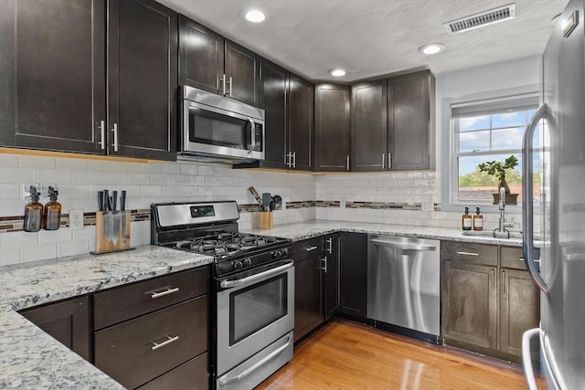 12 School St Unit 3, Salem, MA 01970 - kitchen featuring stainless steel appliances, a sink, light wood-type flooring, light stone counters, and backsplash