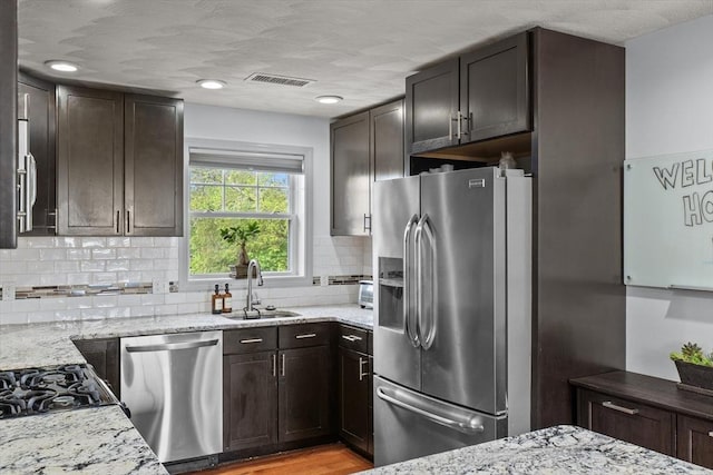 12 School St Unit 3, Salem, MA 01970 - kitchen with stainless steel appliances, a sink, light stone counters, backsplash, and dark brown cabinets