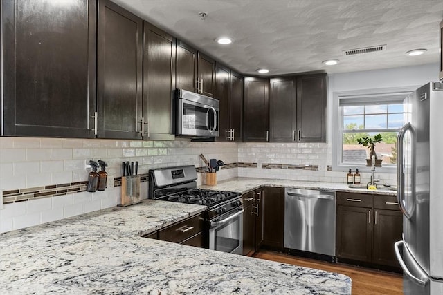 12 School St Unit 3, Salem, MA 01970 - kitchen featuring stainless steel appliances, light stone countertops, wood finished floors, tasteful backsplash, and recessed lighting