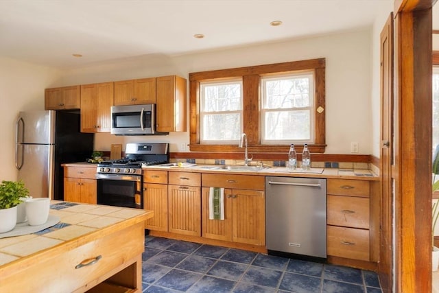 kitchen with appliances with stainless steel finishes, sink, and tile countertops