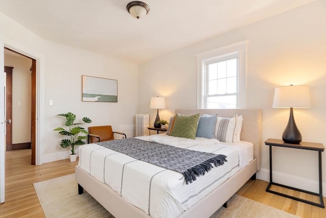 bedroom with radiator heating unit and light hardwood / wood-style floors