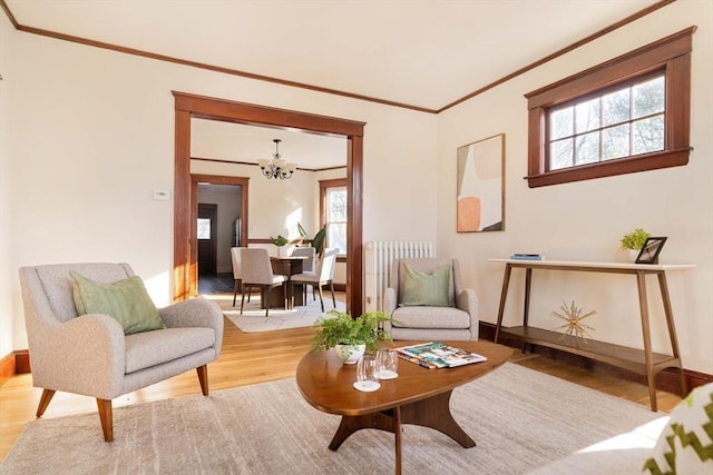 living area with radiator, wood-type flooring, an inviting chandelier, and a healthy amount of sunlight