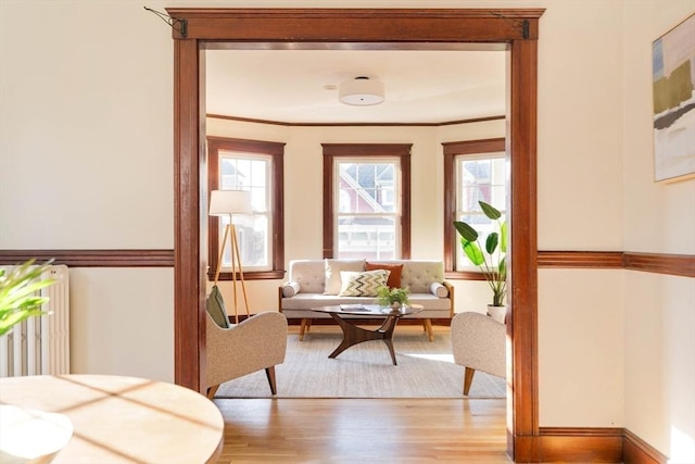 living room featuring radiator heating unit, ornamental molding, and light hardwood / wood-style flooring