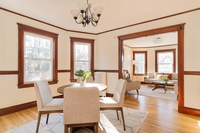 dining area featuring light hardwood / wood-style floors, ornamental molding, and an inviting chandelier