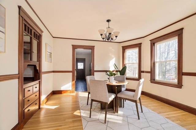 dining room with light hardwood / wood-style flooring, ornamental molding, and an inviting chandelier