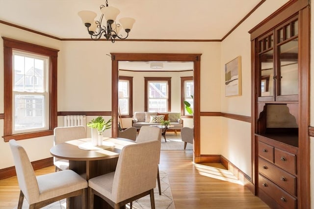 dining room with light hardwood / wood-style flooring, crown molding, a notable chandelier, and a healthy amount of sunlight