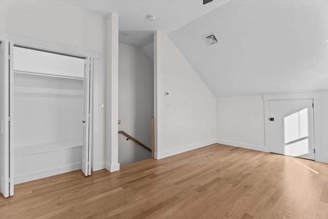 additional living space with light hardwood / wood-style flooring and lofted ceiling