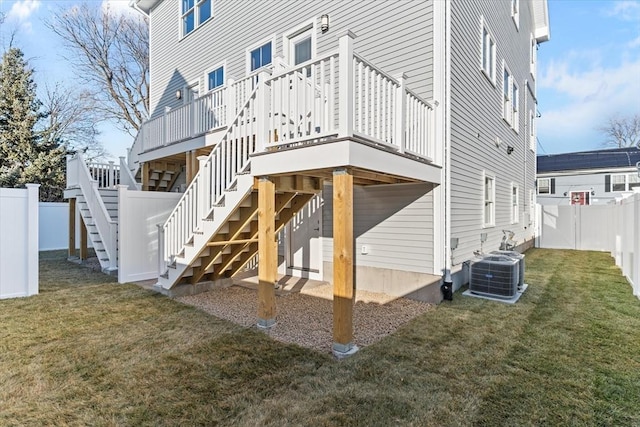 rear view of house featuring a lawn, central AC, and a deck