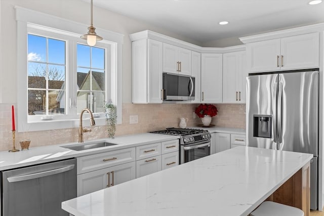 kitchen with light stone counters, stainless steel appliances, sink, pendant lighting, and white cabinetry