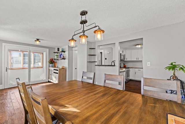 dining area featuring dark wood-type flooring and a textured ceiling