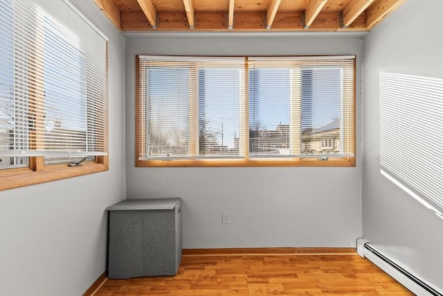 unfurnished room featuring beam ceiling, wood ceiling, baseboard heating, and light hardwood / wood-style flooring