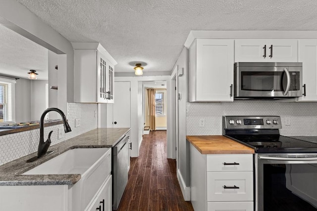 kitchen with dark hardwood / wood-style flooring, backsplash, stainless steel appliances, sink, and white cabinets