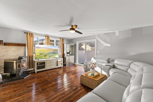 living room with dark hardwood / wood-style flooring, a wood stove, and ceiling fan