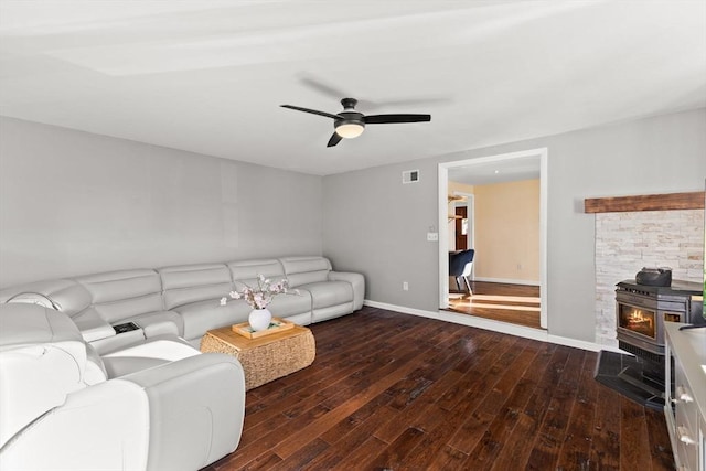 living room featuring a wood stove, ceiling fan, and dark hardwood / wood-style flooring