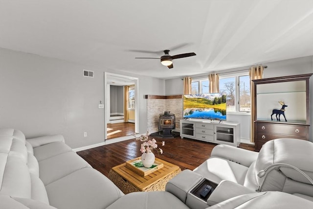 living room with ceiling fan, wood-type flooring, and a wood stove