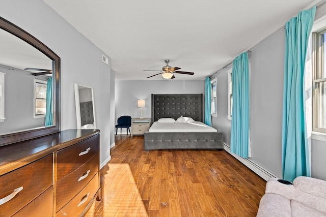 bedroom with ceiling fan, hardwood / wood-style floors, and a baseboard radiator