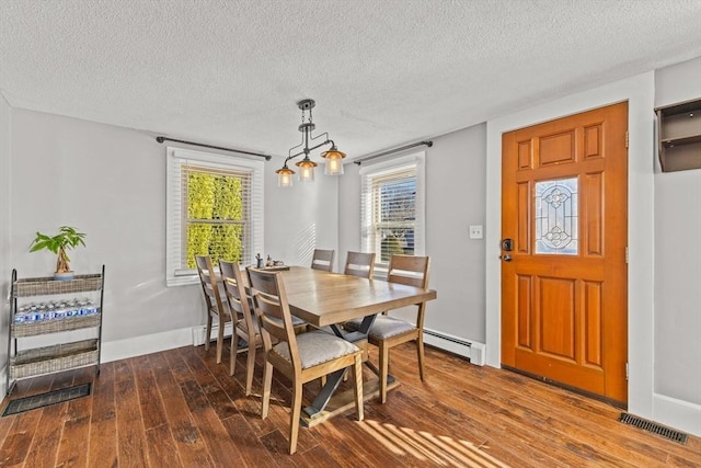 dining space with dark hardwood / wood-style flooring, a textured ceiling, and a baseboard heating unit