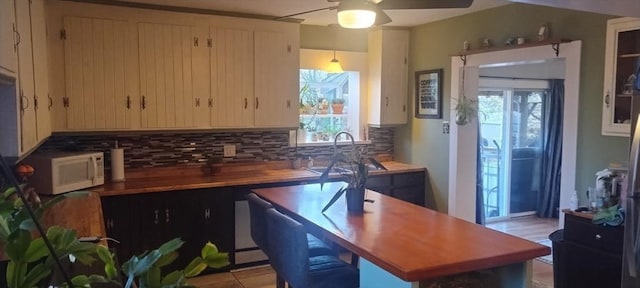 kitchen featuring butcher block counters, sink, backsplash, and ceiling fan