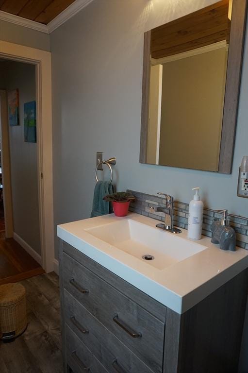 bathroom with crown molding, vanity, and hardwood / wood-style flooring