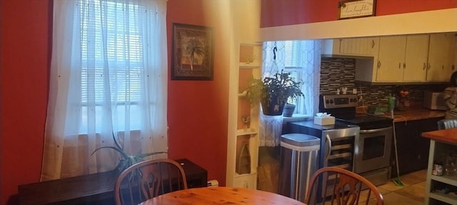 kitchen featuring tasteful backsplash, light tile patterned floors, electric range, and a wealth of natural light