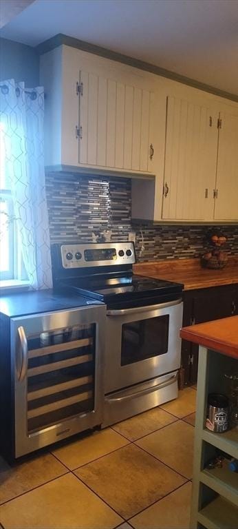 kitchen with wine cooler, white cabinetry, light tile patterned floors, stainless steel electric stove, and backsplash