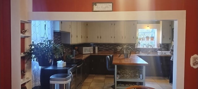 kitchen with tasteful backsplash, cream cabinets, sink, and light tile patterned floors