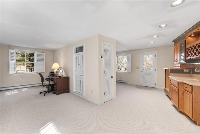 office area with plenty of natural light, baseboard heating, and light carpet