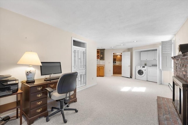 office area featuring washer and dryer, a brick fireplace, baseboards, and carpet floors