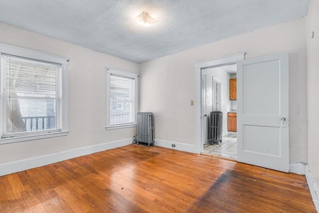 127-129 Blue Hills Pkwy, Milton, MA 02186 - spare room featuring radiator, light wood-style floors, and a textured ceiling