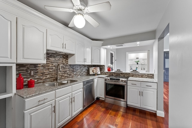 kitchen with decorative backsplash, appliances with stainless steel finishes, dark wood-type flooring, sink, and white cabinetry