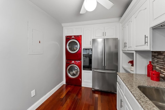 kitchen with white cabinets, dark hardwood / wood-style floors, light stone countertops, stacked washer / dryer, and stainless steel refrigerator