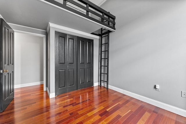 unfurnished bedroom with a closet and dark wood-type flooring