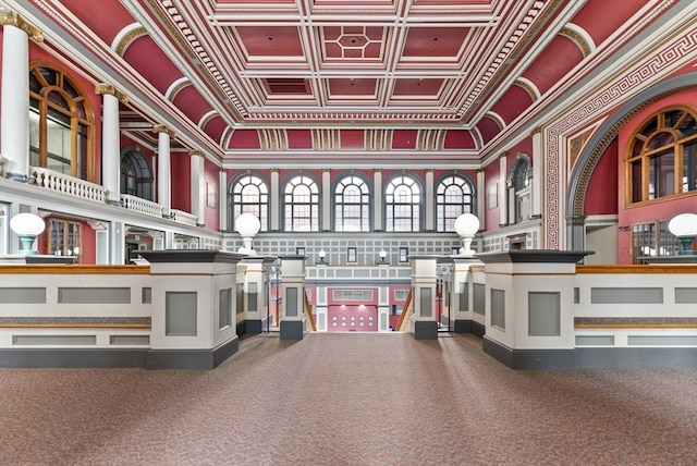 misc room with a towering ceiling, carpet floors, ornamental molding, and coffered ceiling