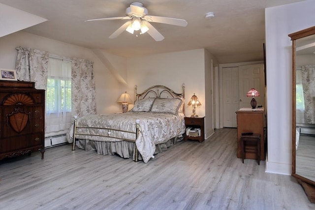 bedroom featuring a ceiling fan, baseboard heating, and wood finished floors