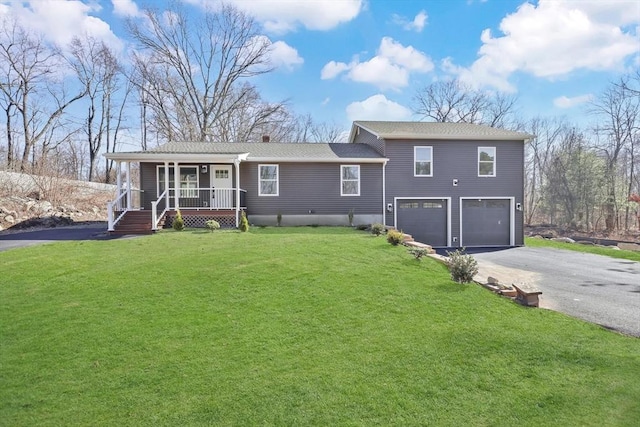 split level home with aphalt driveway, covered porch, an attached garage, and a front yard