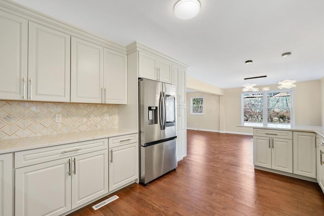 kitchen featuring visible vents, dark wood-type flooring, light countertops, decorative backsplash, and stainless steel refrigerator with ice dispenser