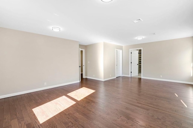 unfurnished room featuring visible vents, dark wood-type flooring, and baseboards