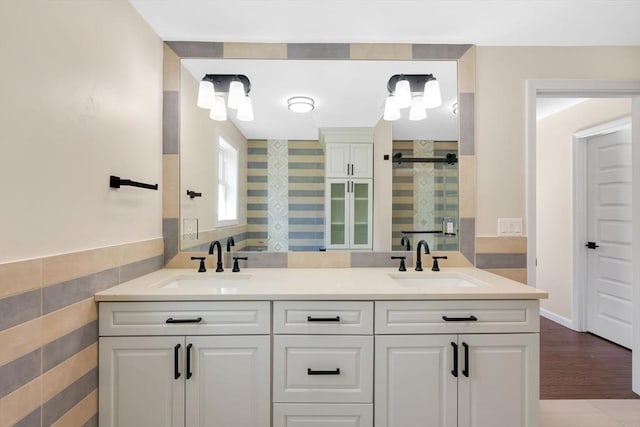 full bath with double vanity, a stall shower, wood finished floors, and a sink