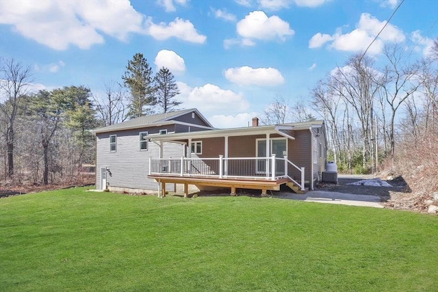 rear view of house with central air condition unit, a lawn, covered porch, and a chimney