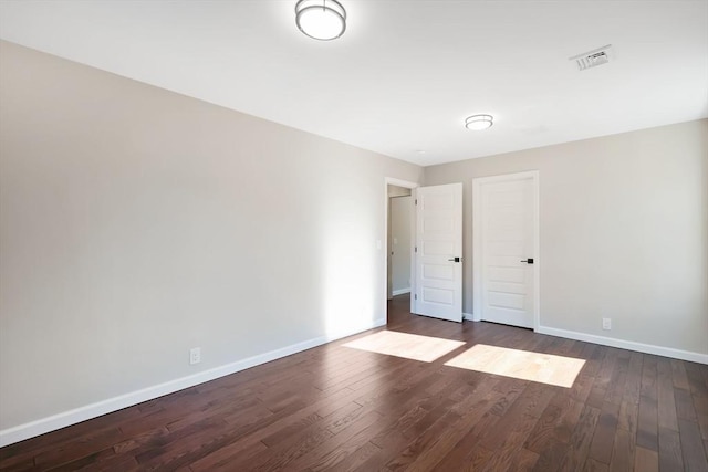 unfurnished bedroom featuring dark wood-style floors, visible vents, and baseboards