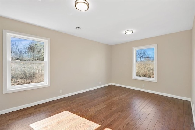 empty room with visible vents, baseboards, and dark wood finished floors