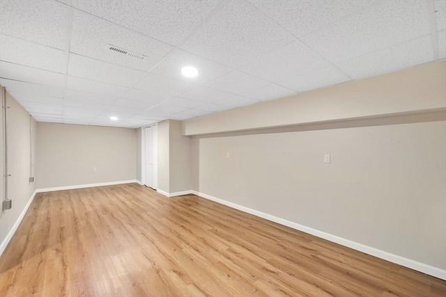 finished basement featuring a drop ceiling, visible vents, baseboards, and wood finished floors